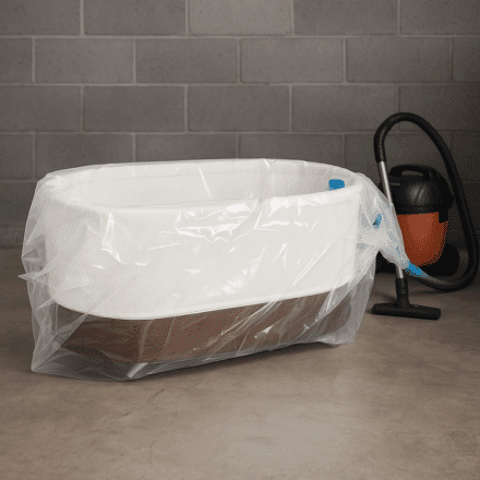 Snoo Smart Sleeper bassinet stored inside a 3D vacuum storage bag with a modern vacuum cleaner nearby on a garage floor