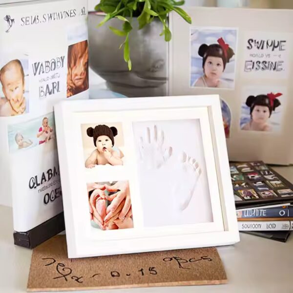 White clay baby handprint and footprint photo frame displayed on a nursery shelf with soft toys and decor