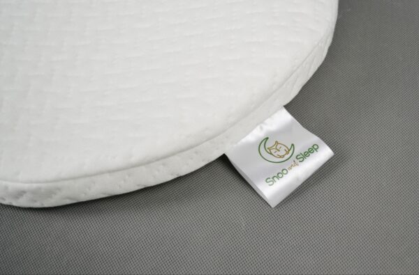 Close-up of Snoo-compatible bassinet mattress showing Snoo and Sleep brand label stitched into corner.